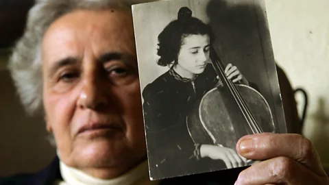 Anita Lasker-Wallfisch holding a photograph of herself when she was younger playing the cello (Credit: Getty Images)