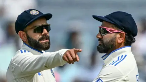 India's Virat Kohli talks with his captain Rohit Sharma (R) during the second day of the second Test cricket match between India and New Zealand at the Maharashtra Cricket Association Stadium in Pune on October 25, 2024.