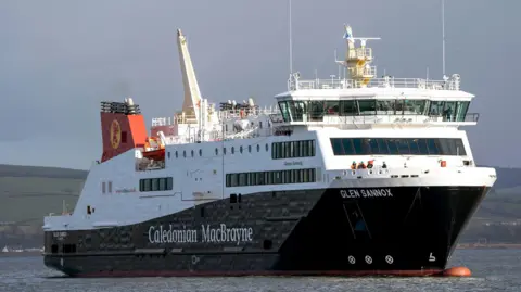 A black and white ship with red funnels with Caledonian MacBrayne written the side, sailing on the River Clyde with hills in the background