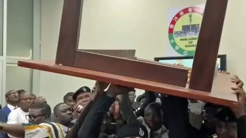 Lawmakers lift a wooden tables above their heads