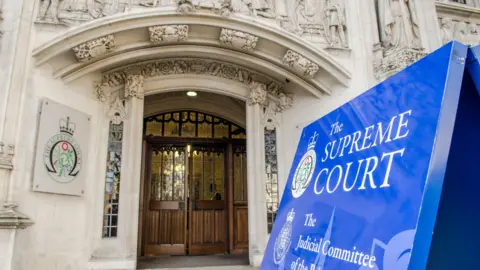 Entrance of the Supreme Court building in London. There is a large blue sign marking the door into the court.