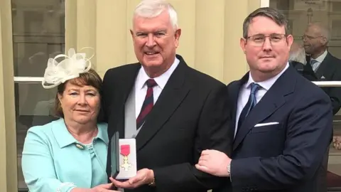 The Peterson family, Maggie, Alan and Hywel, outside Buckingham Palace after Alan received his OBE