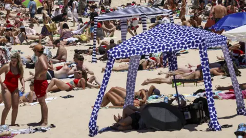 Beachgoers are seen on the sand on Christmas Day at Bondi Beach in Sydney on December 25, 2024