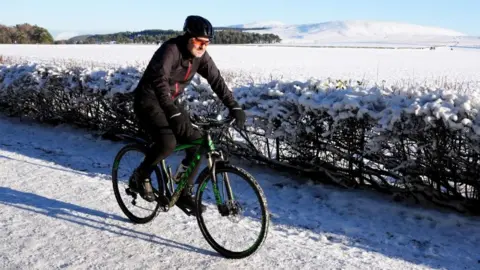 A person cycles through snow in the Pentland Hills, Balerno, Edinburgh