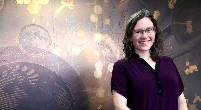 Catherine Elder poses in front of a brown-colored mural of the planets.