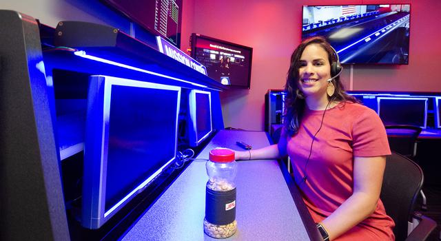 Samalis Santini De Leon poses for a photo with a jar of lucky peanuts in JPL's Space Flight Operations Center.