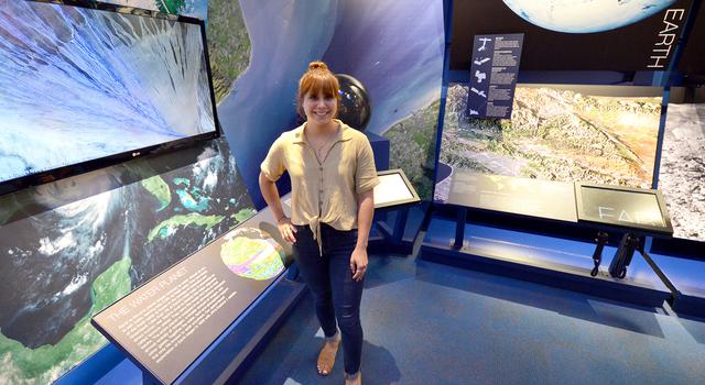 Vicky Espinoza stands in front of an Earth science display at JPL