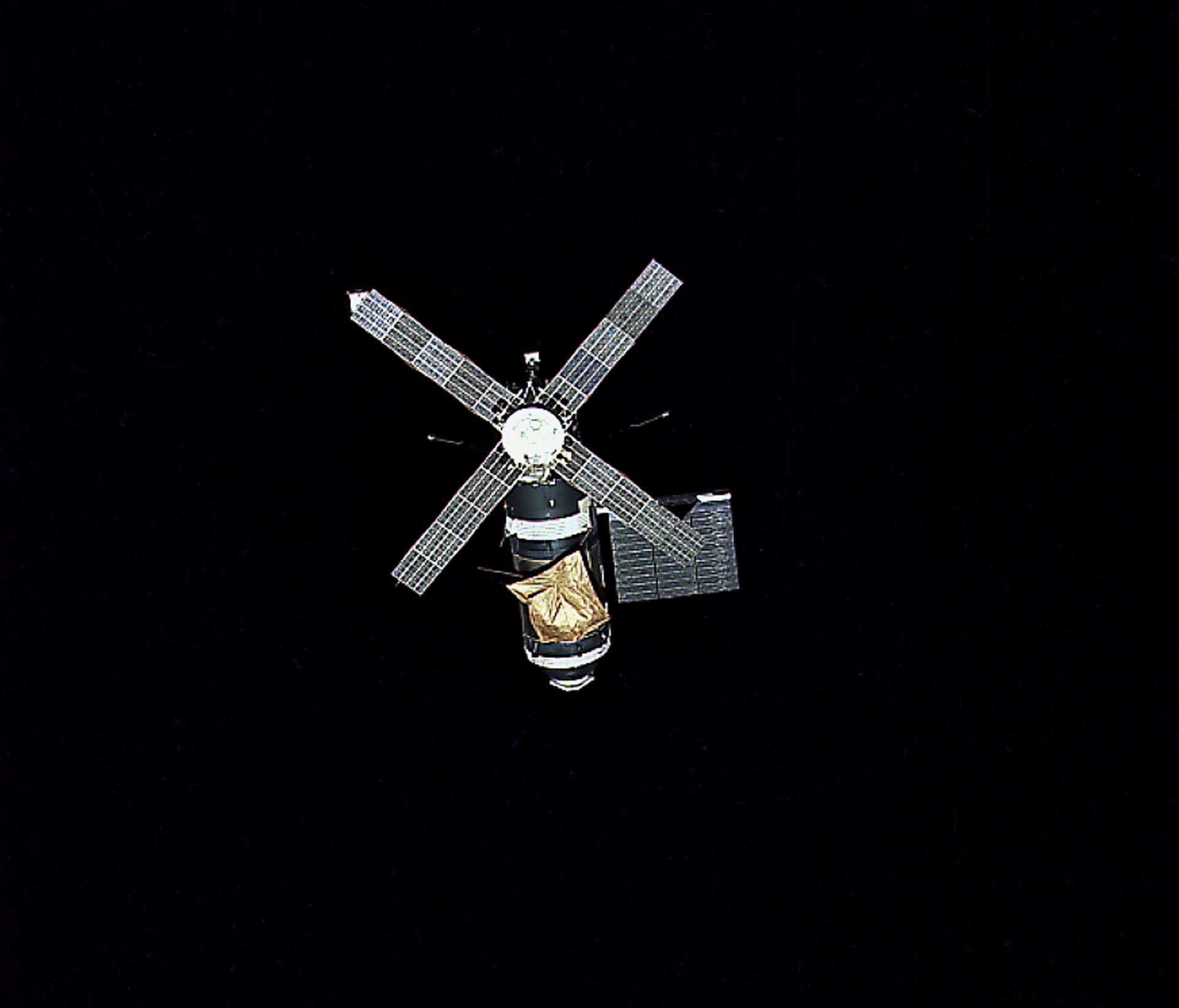 Skylab with its parasol sunshade is seen against the darkness of space by the Skylab 2 crew as it departs for Earth.