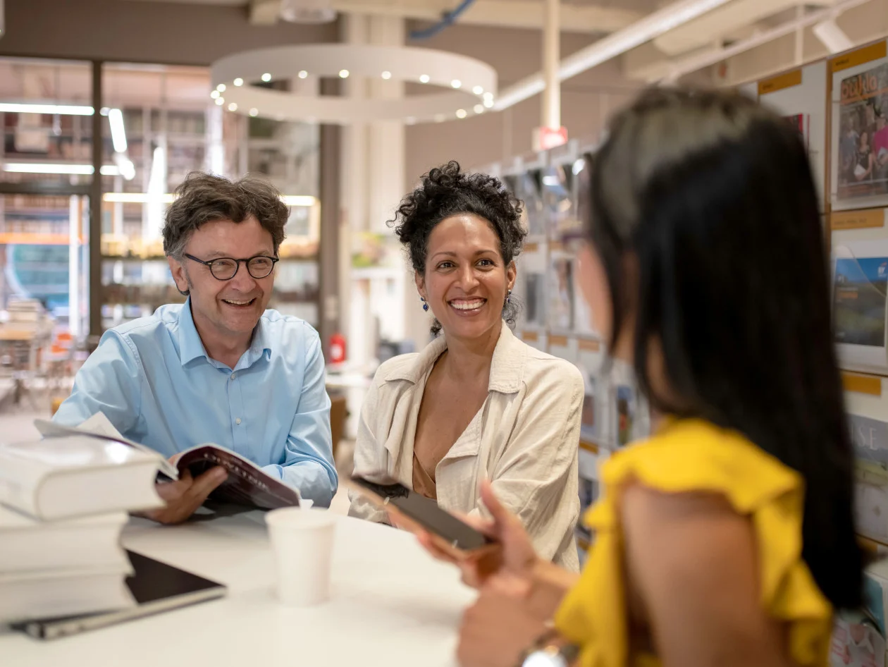 Two people smiling at a person who's head is turned away from the camera