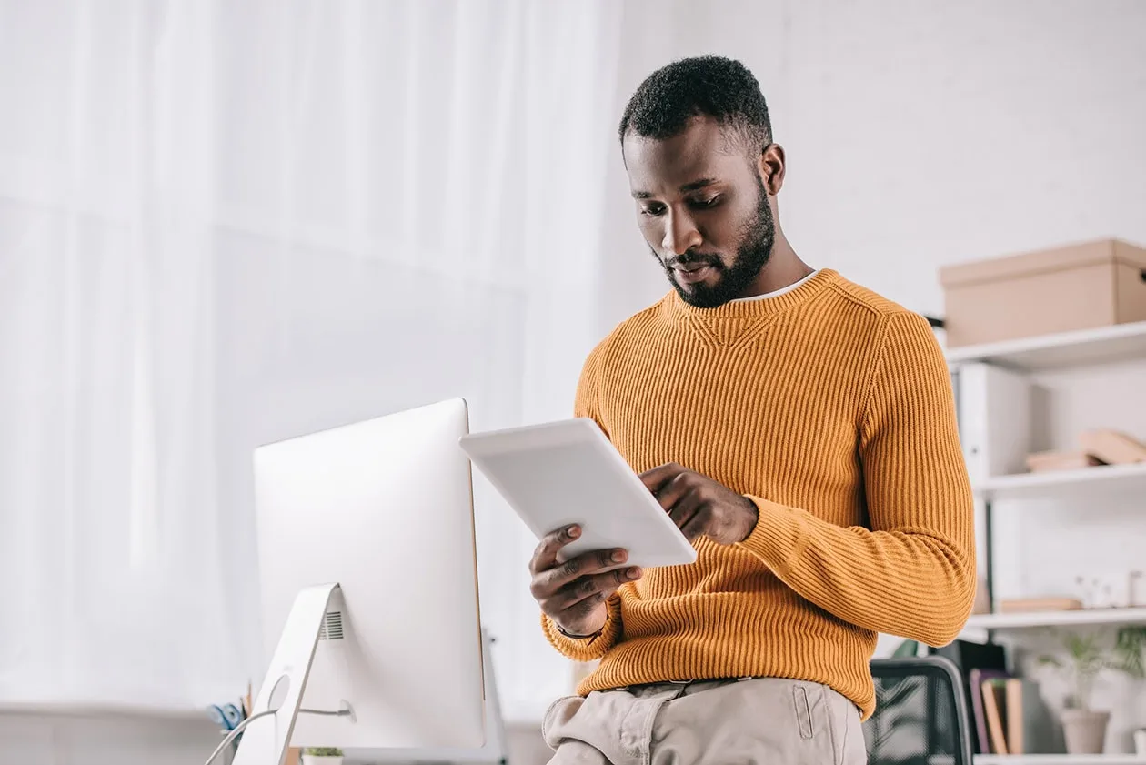 Man standing at desk and looking at iPad 