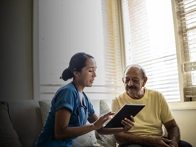 Mexican nurse with tablet sitting with a patient