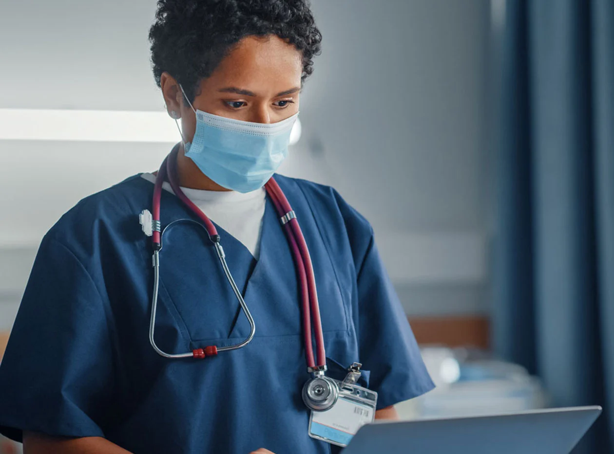 Male nurse in mask works on laptop