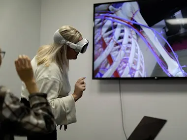 Elsevier's Global Medical Education team works on Complete HeartX, designed for Apple Vision Pro. The woman closest to the screen is wearing an Apple Vision pro headset.