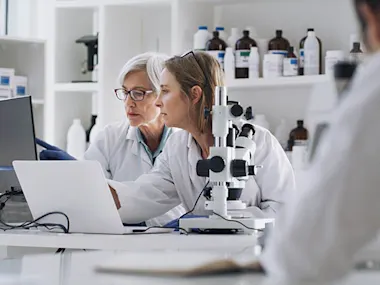 Photo depicting two women and a man working in a pharmaceutical laboratory (DMP/E+ via Getty Images)