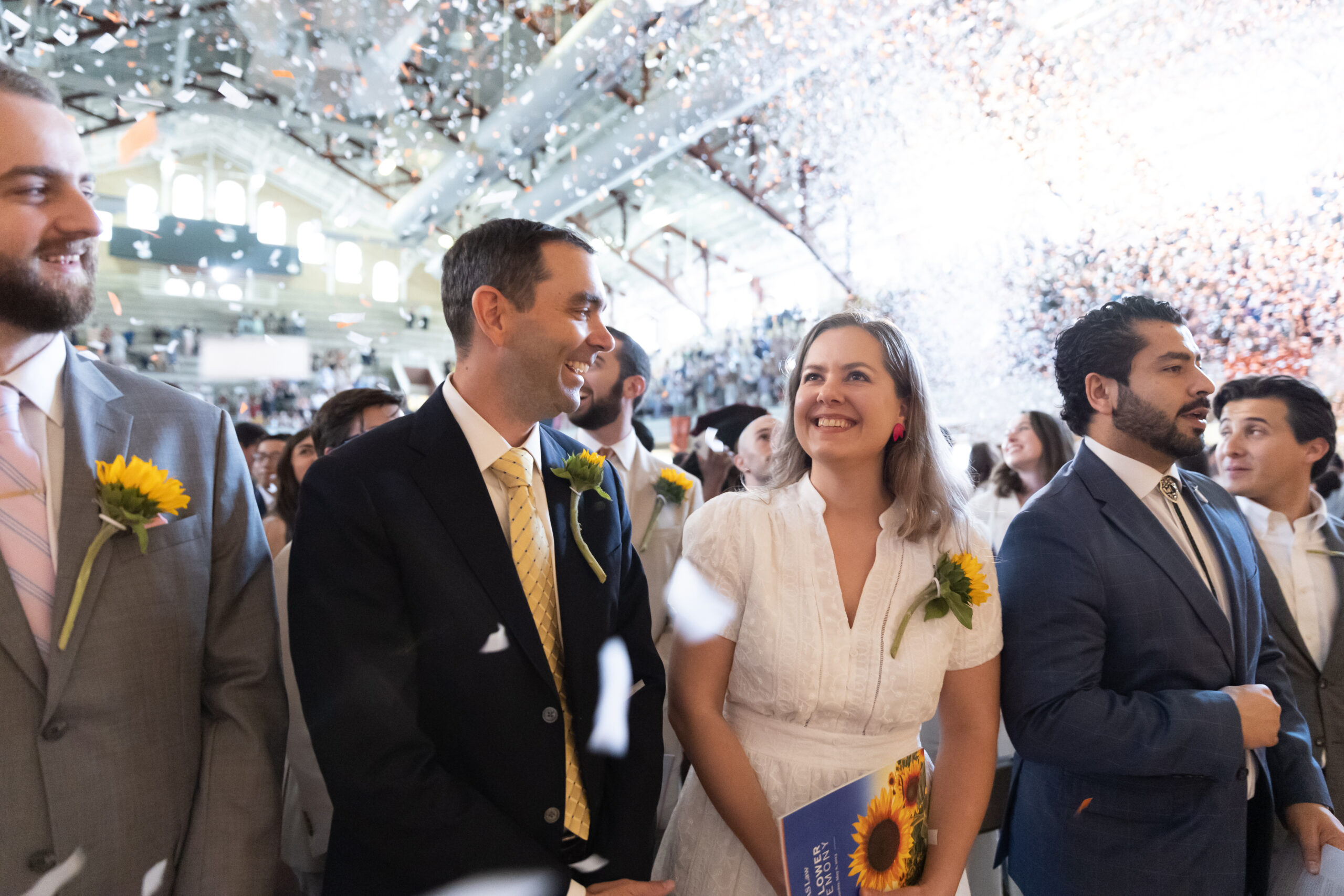 focus on two students smiling with confetti falling in background