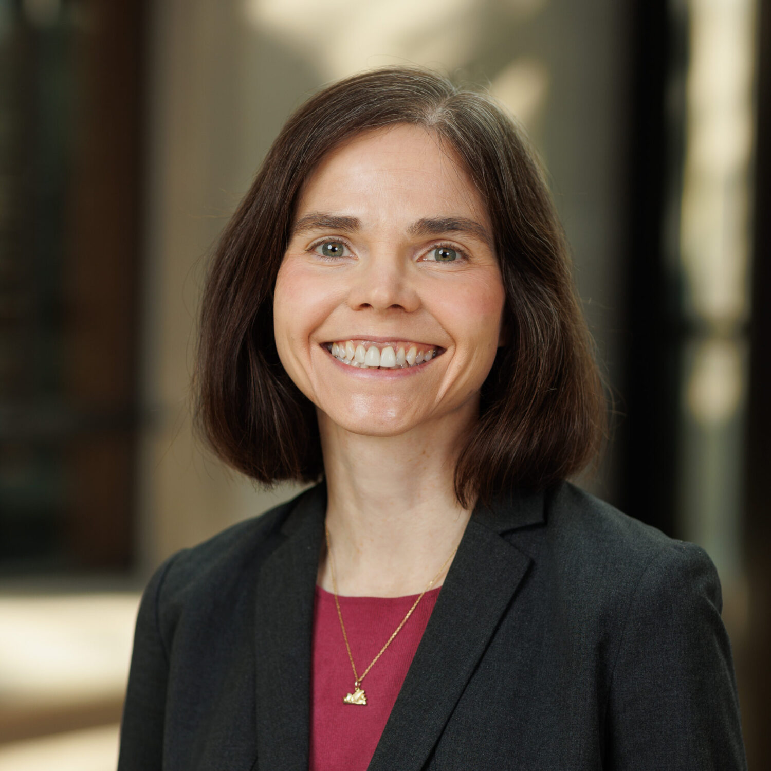 Portrait of woman smiling wearing gray blazer and red shirt