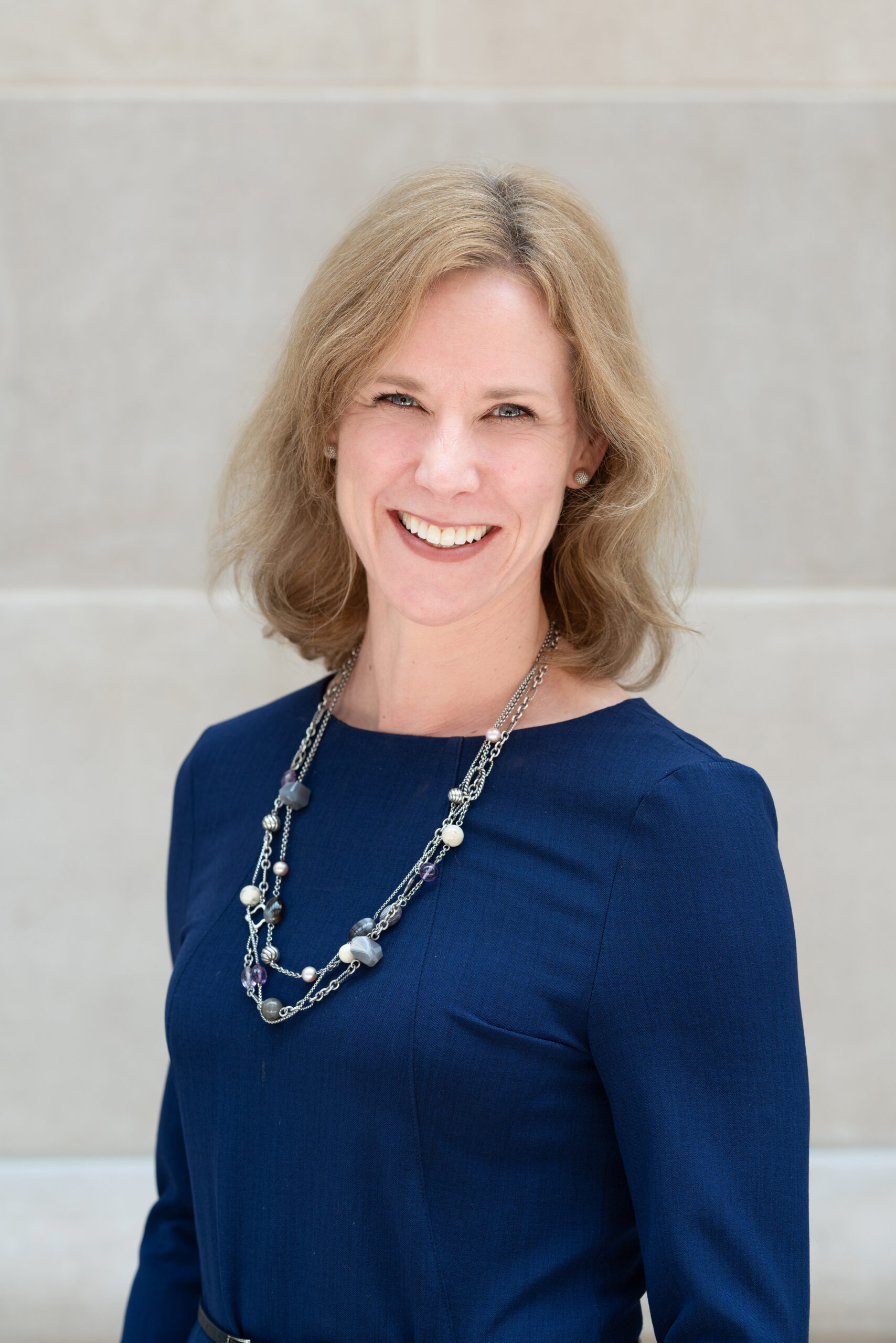 Portrait of Susan Morse wearing a long necklace over a blue blouse.