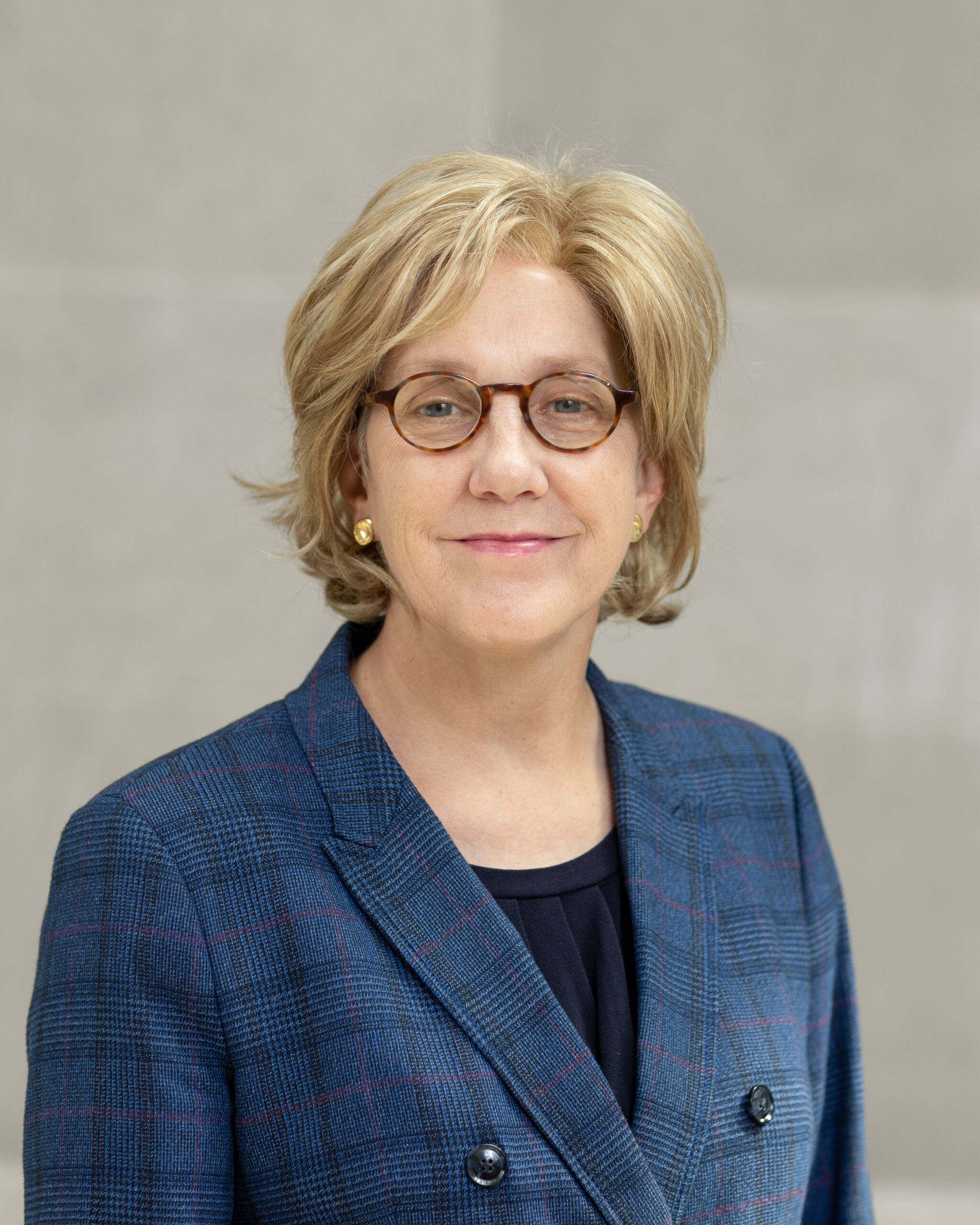 Portrait of Eden Harrington wearing a black shirt under a blue suit jacket.