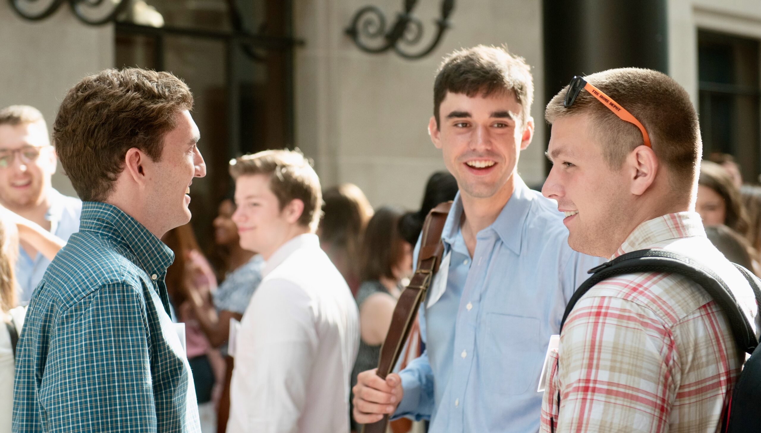 Three men standing in the law school and discussing their classes.