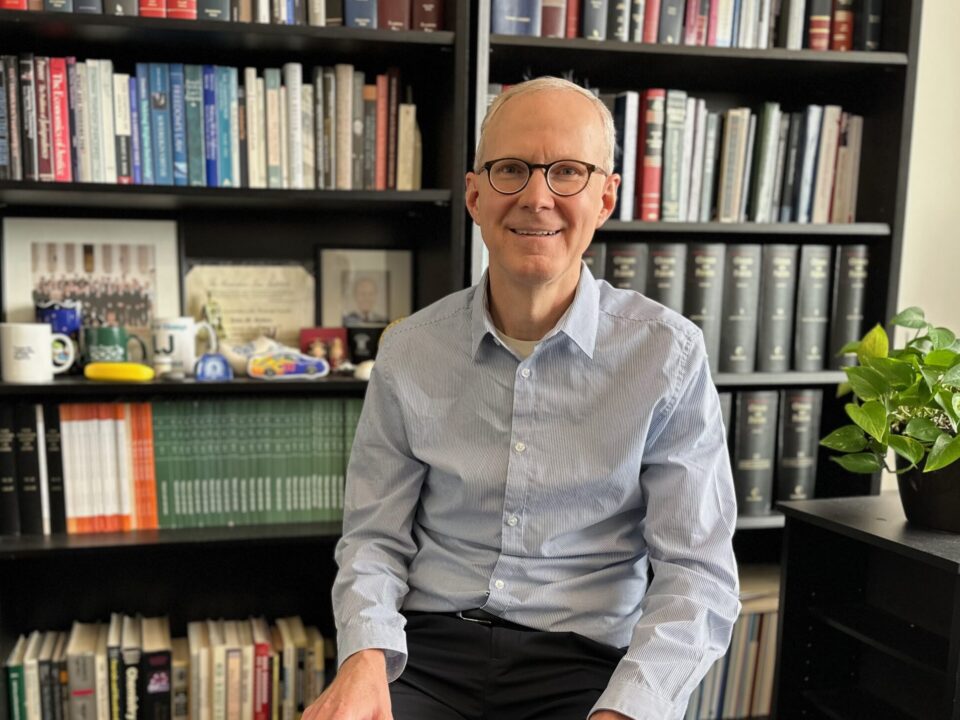 John Golden sits in his office in front if his bookcases.