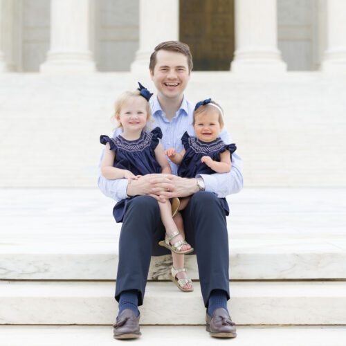 Photo of Reid Coleman and young daughters outside on the steps of the Supreme Court.