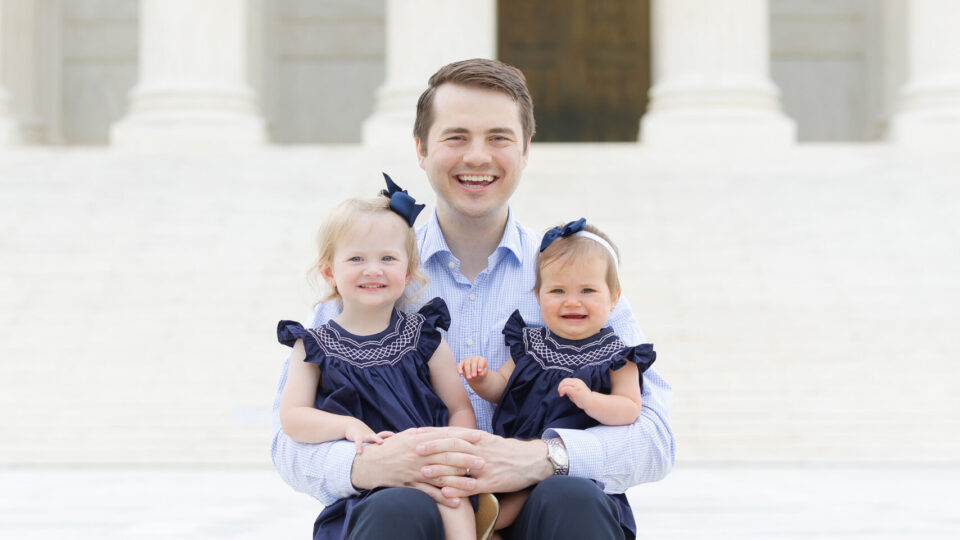 Photo of Reid Coleman and young daughters outside on the steps of the Supreme Court.