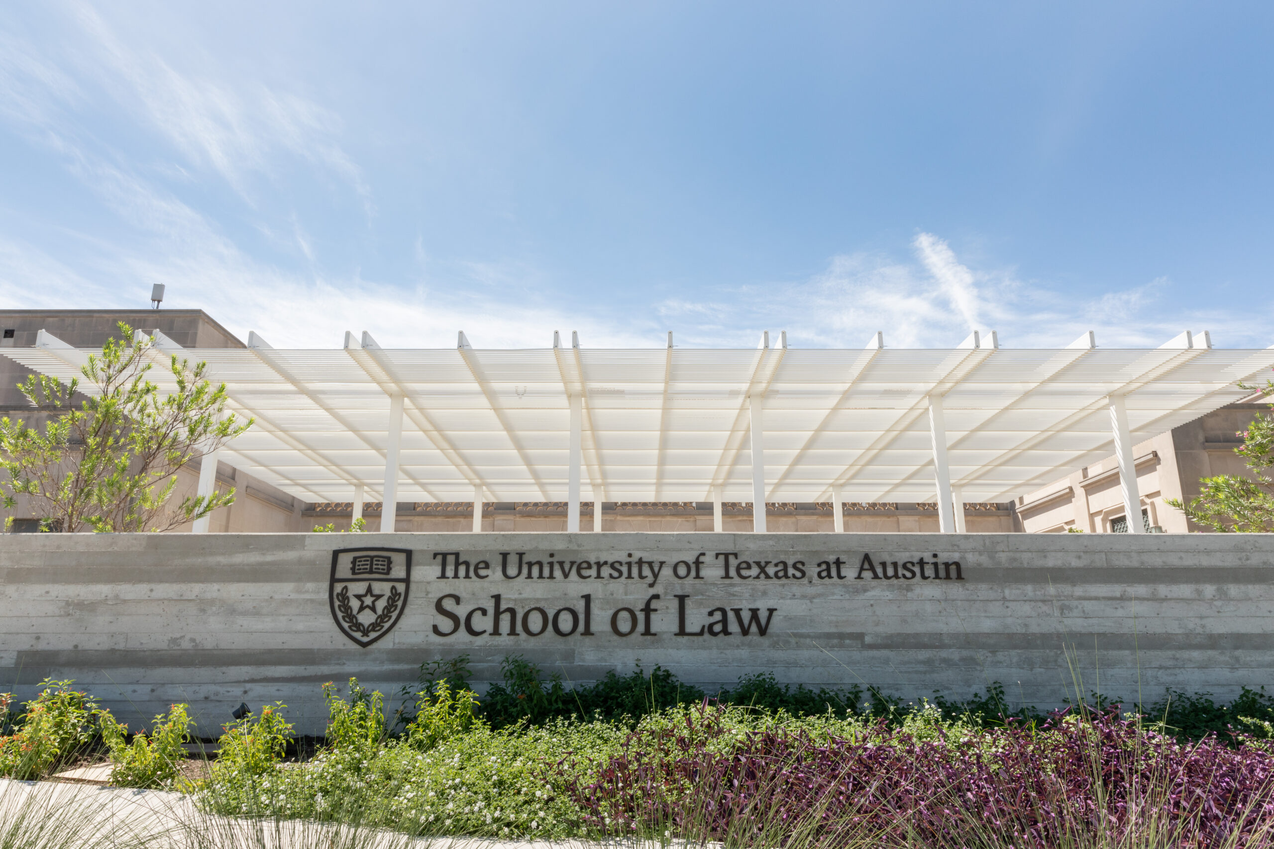 Courtyard entrance to Texas Law with blue skies and green spaces.