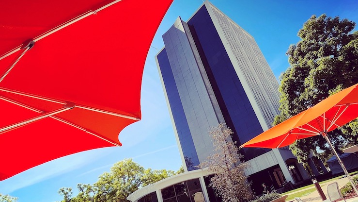 tall building with wading pool partially blocked by orange umbrellas