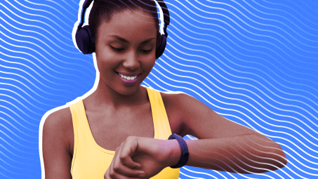 A woman wearing headphones and running gear looking at his smartwatch on her wrist