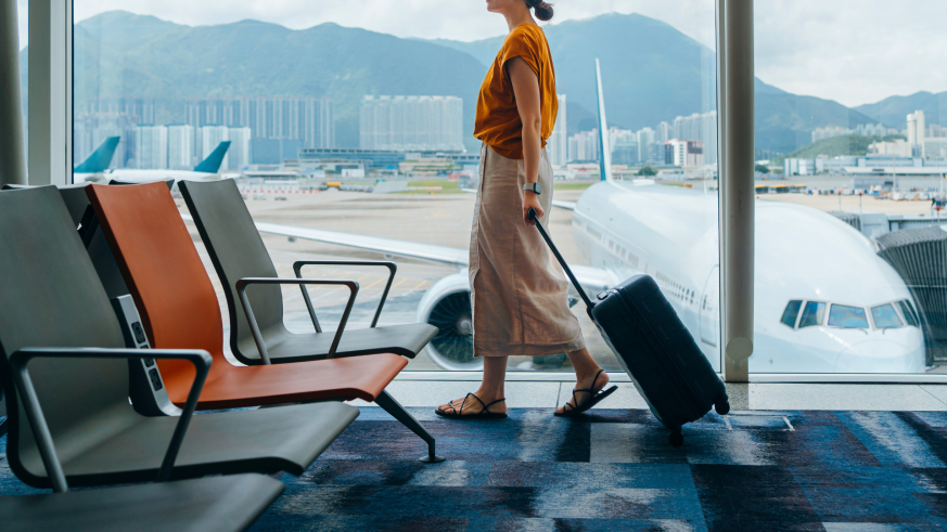 Woman walking through an airport with a wheeled suitcase