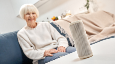 close up of a smart home device with smiling elderly woman in the background