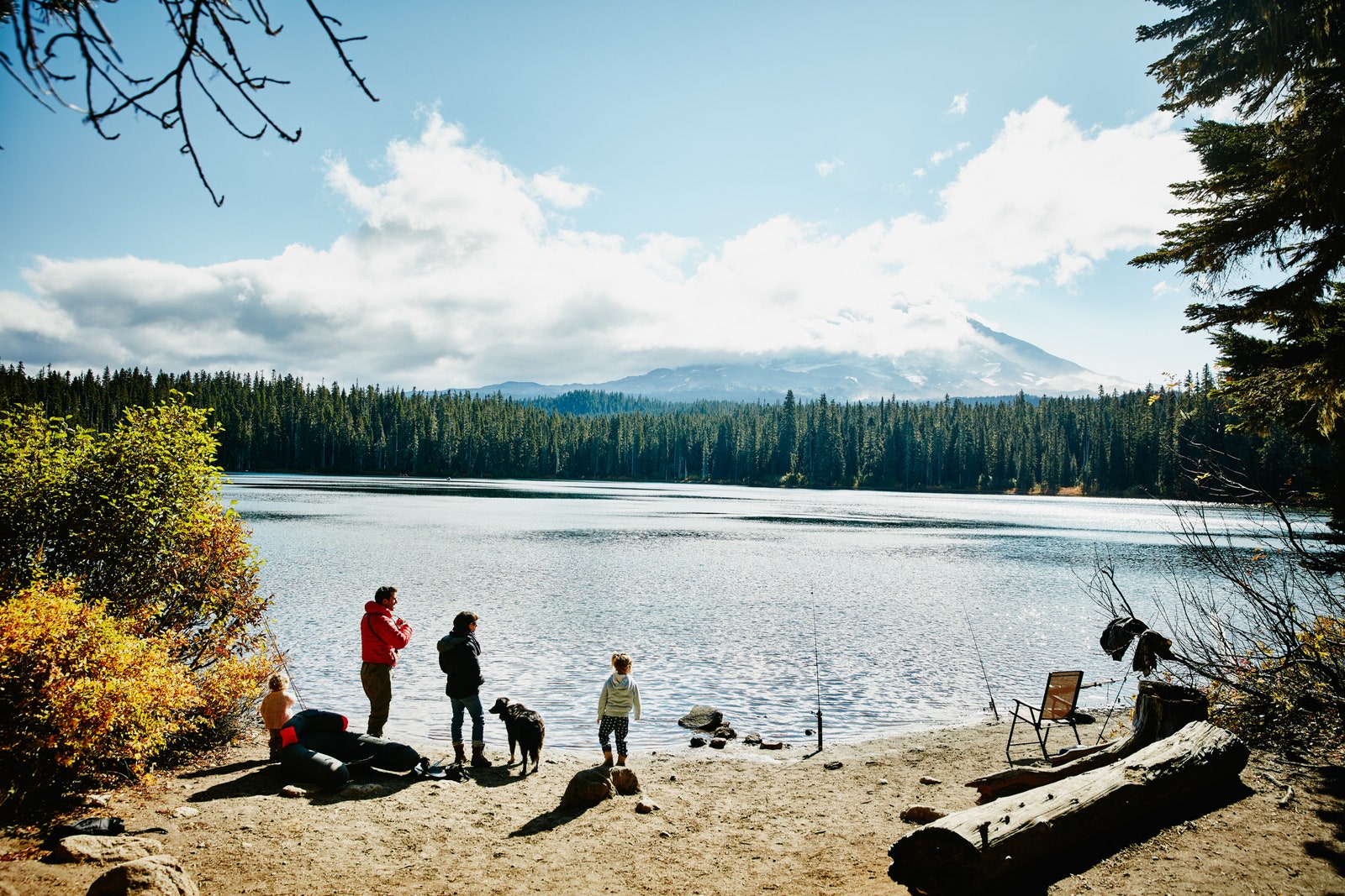 Family playing and fishing on shoreline of lake