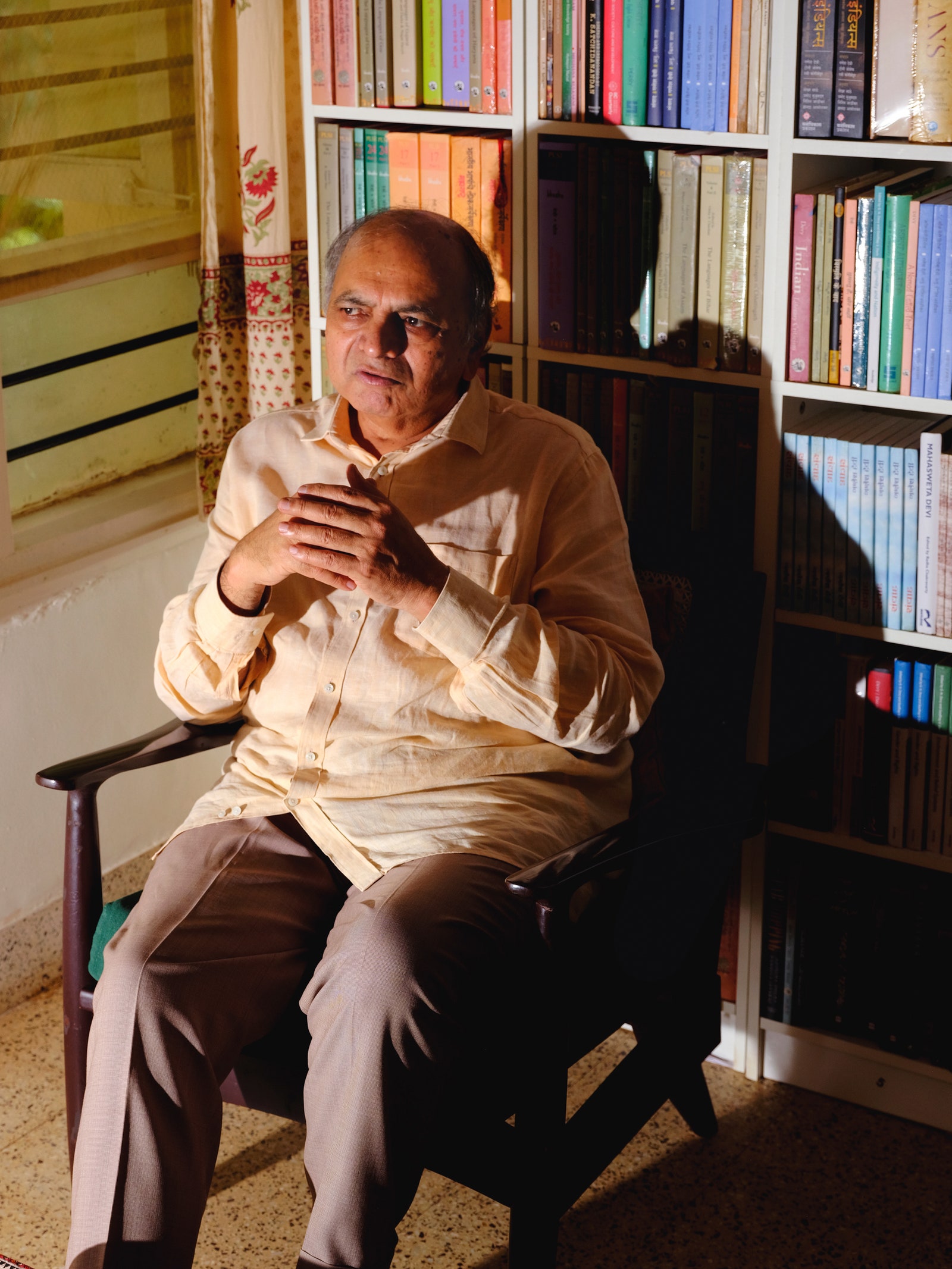 A photograph of Ganesh Devy sitting in a chair.