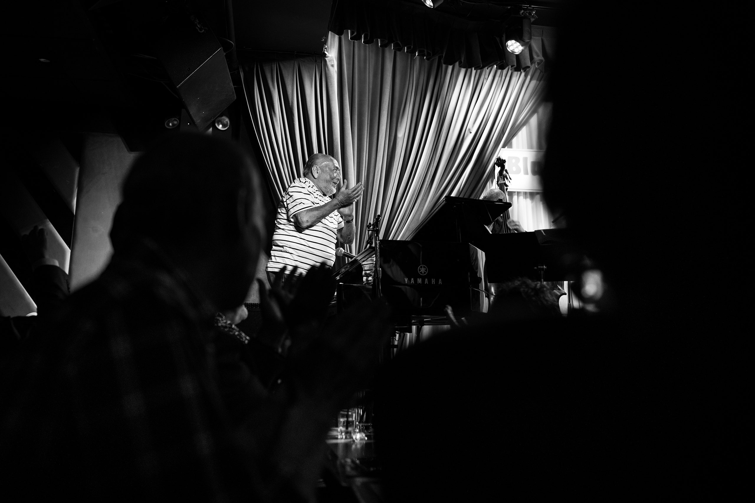 A blackandwhite photo of Eddie Palmieri clapping onstage.