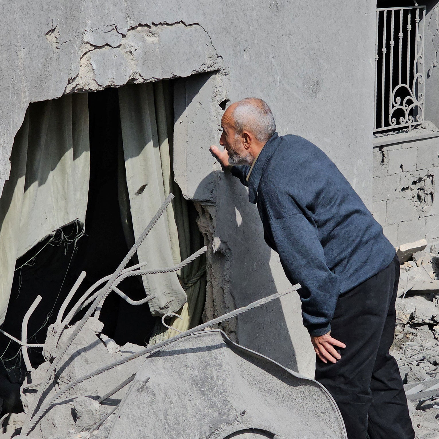 A man inspects a damaged house.