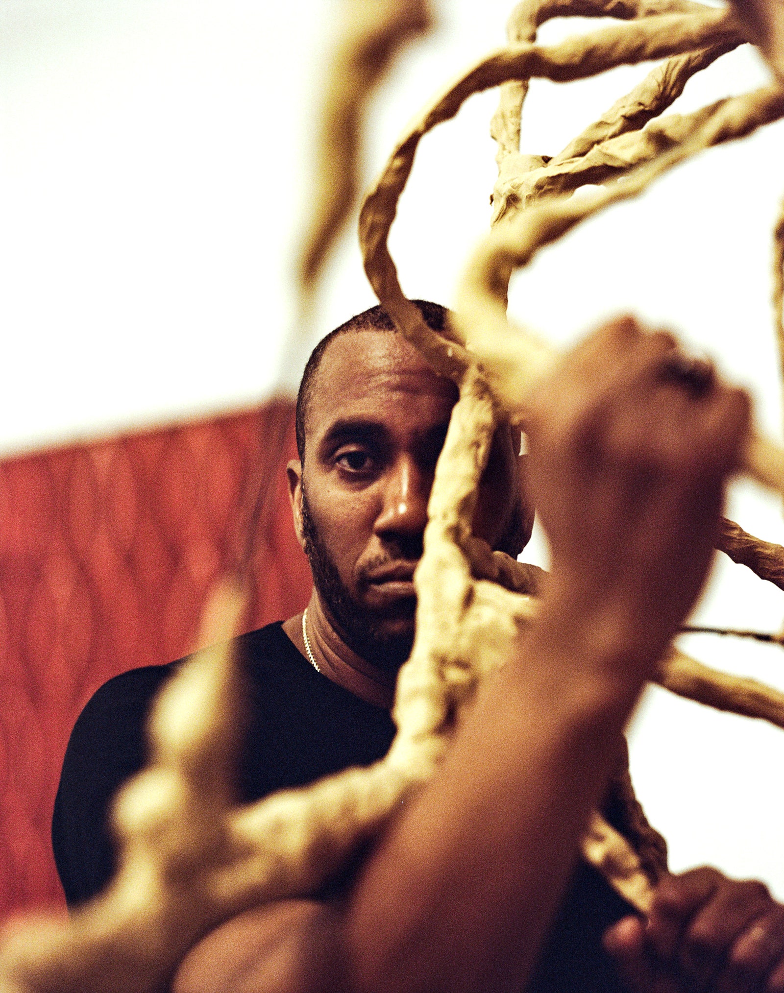 An image of Rashid Johnson behind a partially visible sculpture.