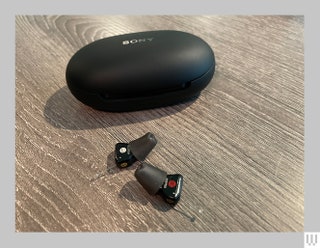 Black inear hearing aids beside a black ovalshaped case