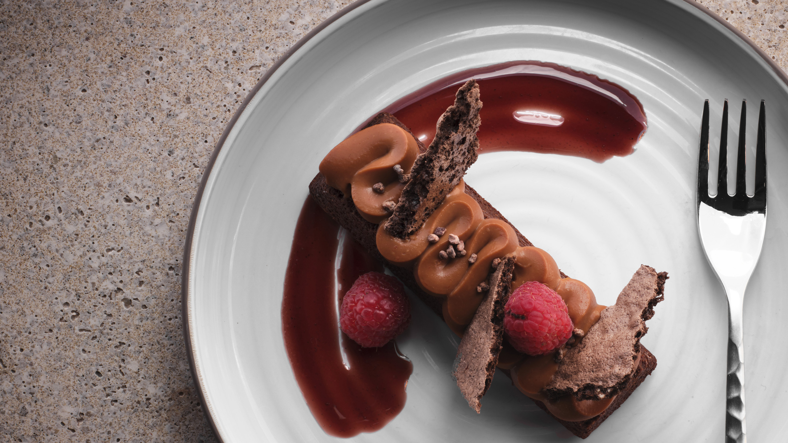 chocolate dessert with raspberry on top on plate with fork served at the Hummingbird restaurant