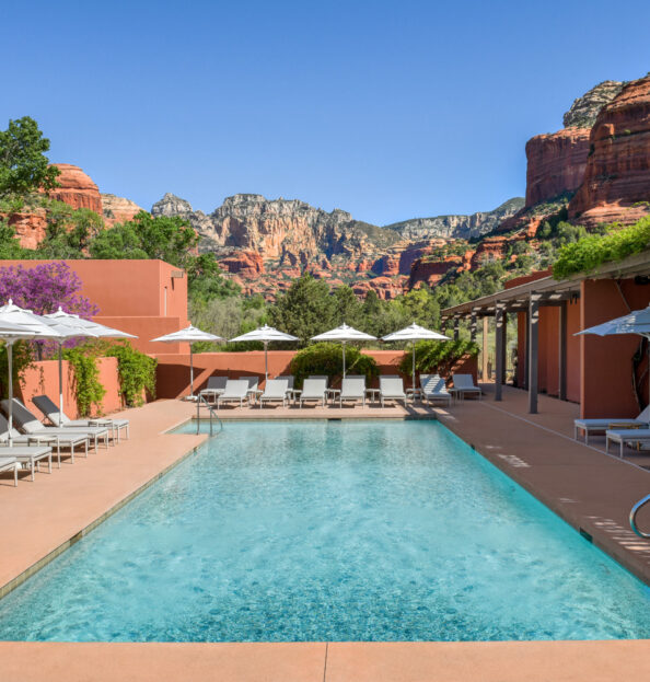 Pool view at Mii amo with white umbrellas and red rocks in the distance