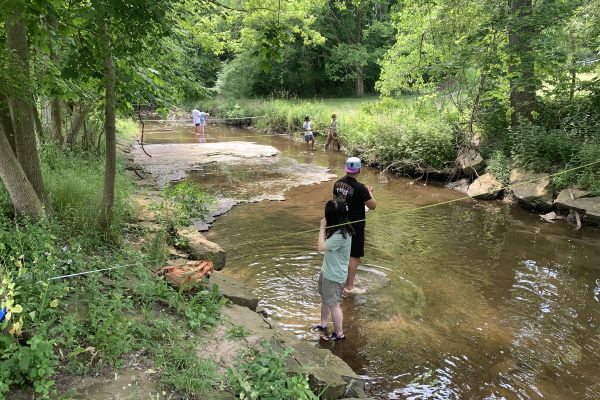 people standing in a body of shallow water fishing