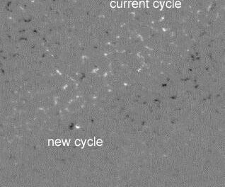 An equator-to-south pole subsection of the Sun on July 23, 2006 shows the location and polarity of magnetic fields as light and dark patches. White indicates polarity rising out of the solar surface, and black indicates polarity into the surface. An eruption of the new cycle is labeled in the lower, high latitude part of the image, and a current cycle low latitude eruption is labeled at the top. Notice the reversed east-west orientation of the eruptions. Magnetic patterns in the northern hemisphere will be reversed, i.e., black-white near the equator for the current cycle and white-black near the poles for the new cycle.