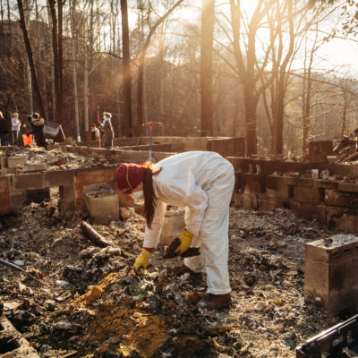 A woman picks up debris at the site of a burned building