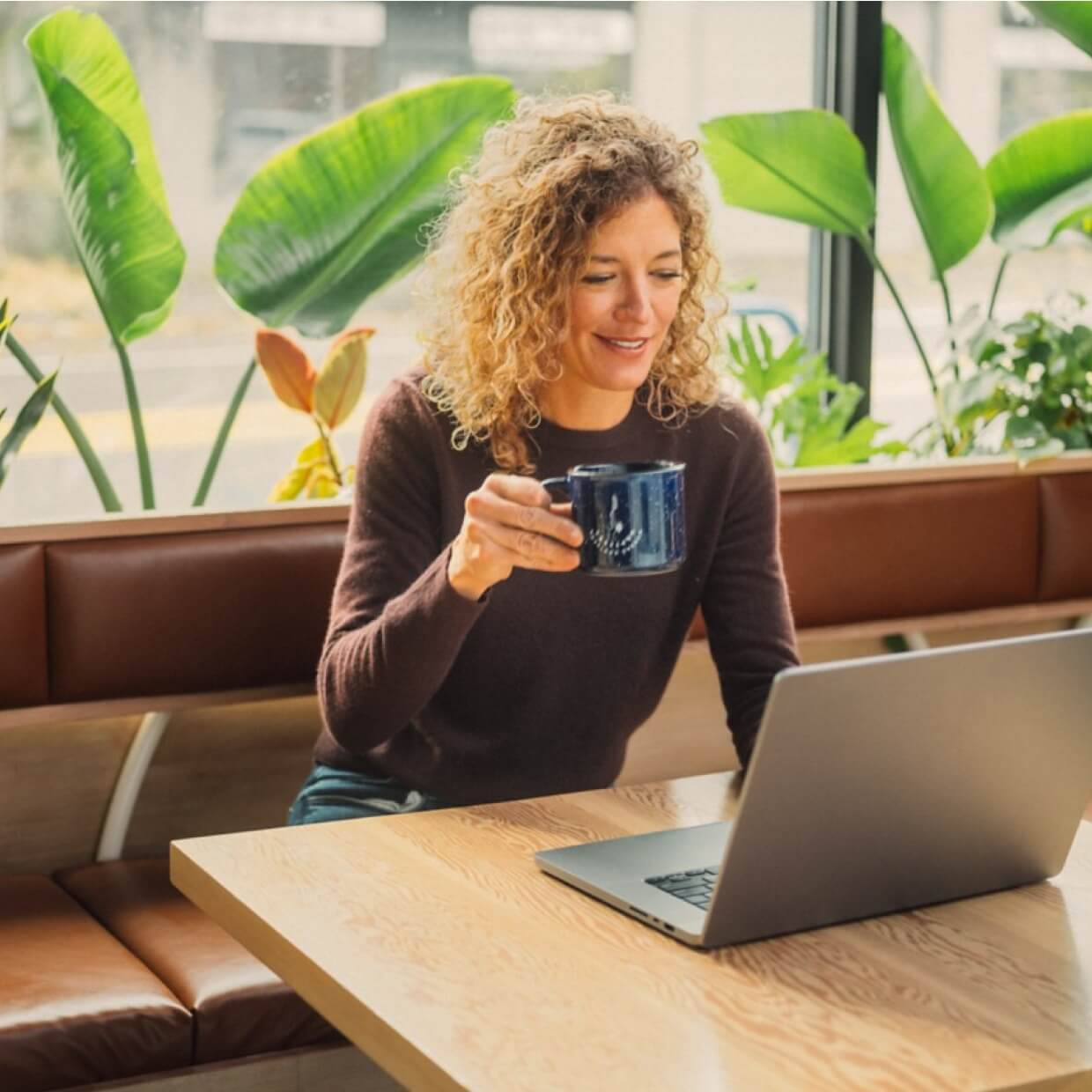 A business person is sitting at a desk reviewing her business on a laptop.