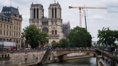 Onlookers await the arrival of the Olympic flame torch near the Notre-Dame Cathedral in central Paris on July 14, 2024.