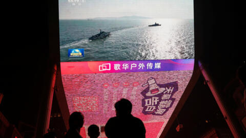 A giant screen shows news footage of military drills conducted in the Taiwan Strait and areas to the north, south and east of Taiwan, by the Eastern Theatre Command of the Chinese People's Liberation