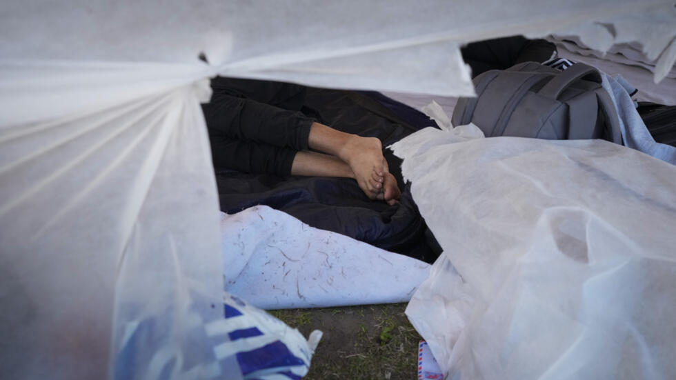 A migrant sleeps outside an overcrowded centre for asylum seekers in Ter Apel, in the Netherlands.