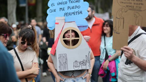 Uma mulher coberta com uma casa de papelão com uma placa dizendo "A única casa que posso pagar" participa, com dezenas de milhares de pessoas, de uma manifestação organizada por mais de 30 organizações (incluindo o Sindicato dos Inquilinos) para exigir o direito à moradia digna, em Madri, em 13 de outubro de 2024.