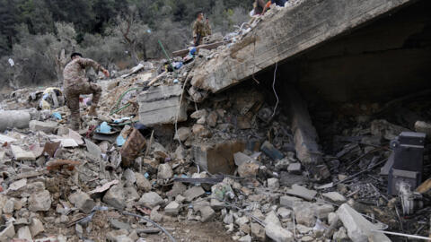 Un soldat libanais gravit les décombre d'un batiment touché par un bombardement israélien, le 15 octobre 2024 dans le village d'Aito.