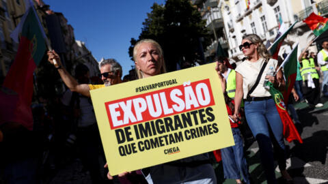 Uma mulher segura um cartaz em uma manifestação do partido Chega contra o que consideram "migração descontrolada e insegurança nas ruas”, em Lisboa, Portugal, em 29 de setembro de 2024.