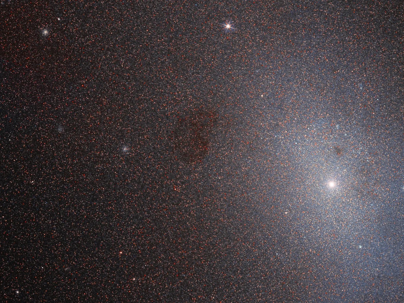 Hubble image of messier 110. A soft light on the right side of the image shrouded by dust and gas.